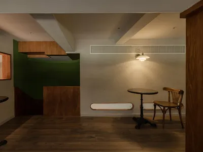 Dining area with a wooden floor, a table, and two chairs, accompanied by a couch near the left wall