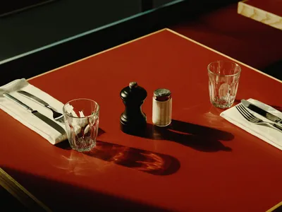 紅桌椅餐廳區域，擺放玻璃杯、鹽罐、胡椒罐與一瓶飲料，營造溫馨舒適的氛圍
