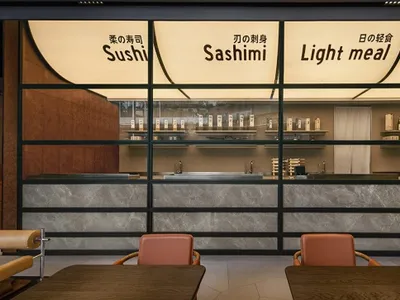 Modern Asian restaurant with a marble counter, sushi bar, and Japanese writing on the walls, creating an inviting atmosphere