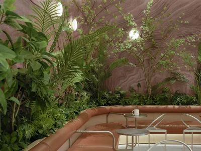 石牆溫馨客餐廳空間，兩組沙發、椅子、咖啡桌與植物，營造溫暖舒適的氛圍