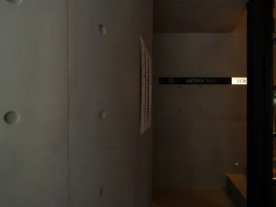 A functional hotel hallway with a white-painted concrete wall, featuring signs and a well-organized atmosphere