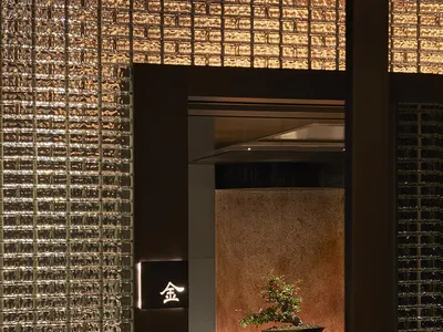 Warm and inviting Asian restaurant with a wooden interior, two chairs, a potted plant, and tiled walls