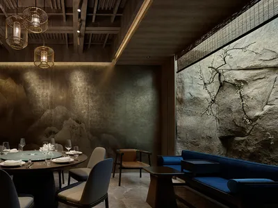現代圓桌餐廳區域，配有椅子、酒杯與杯具，周圍環繞木質與金屬元素，牆面帶灰調