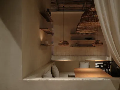 Dining area with a wooden table and chairs, two couches, and a warm ambiance created by dim lighting and wood and stone elements