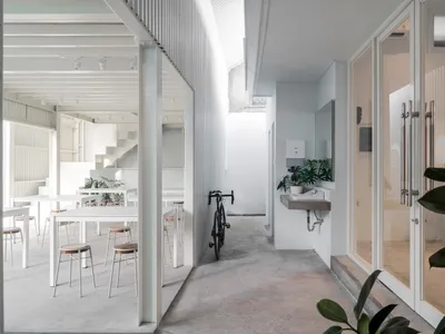 A casual living space with a dining table, two chairs, and a bicycle, set against a neutral background