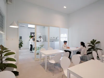 一間休閒餐廳，配有白色椅凳與桌台，人們坐著享用美食，氛圍溫馨親切