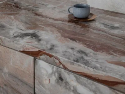 A kitchen countertop with marble and wood features, a cup on a wooden tray, and several bowls arranged around it