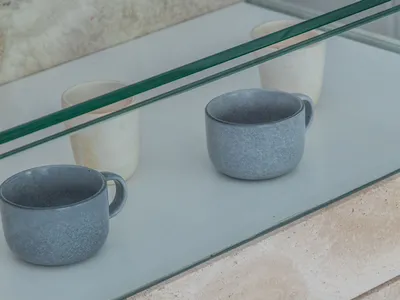 A kitchen countertop with two cups, one near the left and one near the right, made of elegant marble in a clean and organized space