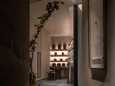 Elegant showroom with glass door, display cases, tables, and cabinets filled with vases, bottles, and other decorative items