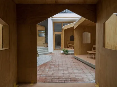 Warm and inviting open concept living area with a brick floor, wooden walls, chairs, a dining table, and a potted plant