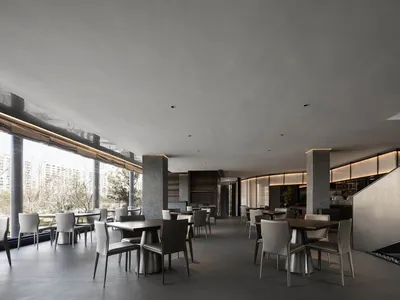 A modern restaurant interior with multiple dining tables and chairs, gray walls, and a spacious atmosphere
