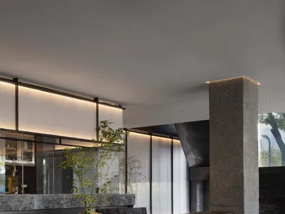Elegant restaurant space with a stone wall, marble countertop, chairs, and a potted plant, featuring high-quality materials and design elements