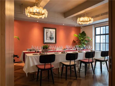 Sophisticated dining space with a long wooden table, multiple chairs, and wine glasses, surrounded by two potted plants