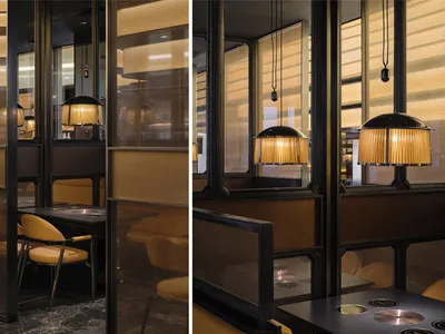 A modern restaurant with a seating area featuring chairs and couches, brown and yellow tones, and natural light
