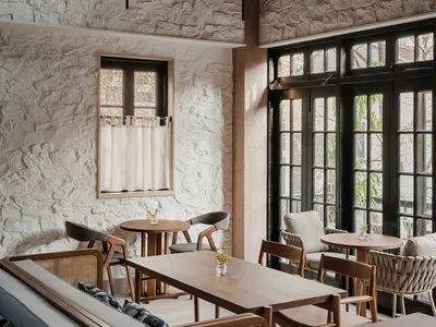 Modern restaurant interior with wooden elements, stone walls, and comfortable seating areas