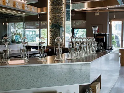 A modern restaurant counter with wine glasses, sleek surfaces, and minimalistic decorations