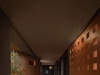 A sleek and modern hotel hallway with a black tile floor, well-lit by overhead lights or natural daylight, featuring two doors on either side