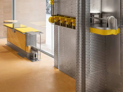 Industrial-style restaurant and bar space with metallic walls, dining tables, and benches, featuring a clock on the wall and a welcoming atmosphere