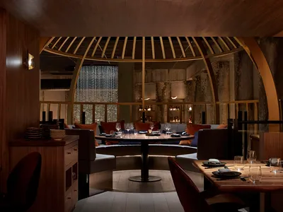Elegant dining space with a large circular table surrounded by chairs, wine glasses, and a sophisticated atmosphere