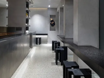 A modern restaurant bar with tile flooring, stools, and chairs in a comfortable seating arrangement