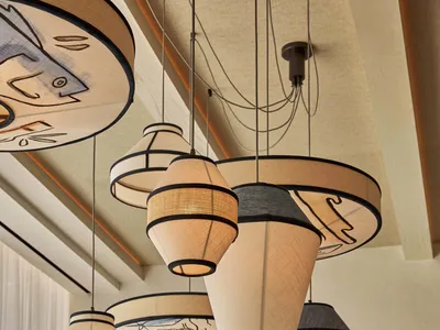 Elegant showroom featuring artistic lighting fixtures made of wood and glass, suspended from the ceiling at varying heights