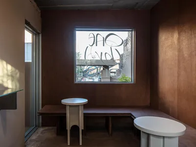 木質牆面與地板的餐廳，設有餐桌、長椅與單椅，背景窗戶灑入自然光線