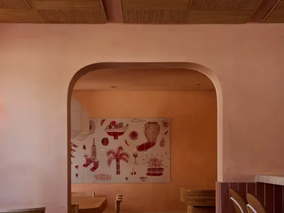 A modern restaurant with a dining area featuring three chairs and two tables, surrounded by pink walls and a warm atmosphere