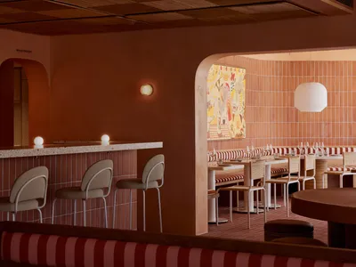 A modern restaurant with a bar area featuring comfortable seating, warm orange walls, and a functional design