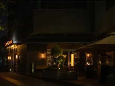 夜晚溫馨吸引人的磚牆外觀餐廳，搭配大樹與盆栽