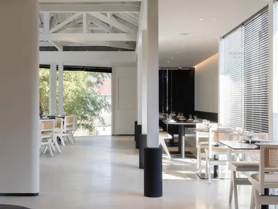 A modern restaurant with a clean and inviting dining area featuring multiple tables and chairs, with wine glasses on some tables, set for service