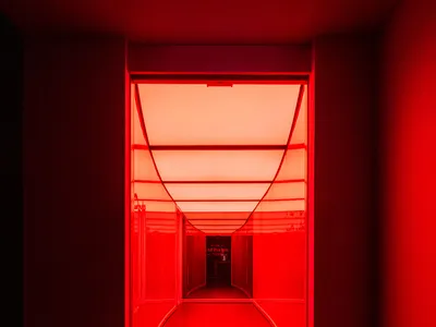 A modern hotel hallway with wooden accents, red walls, and a warm atmosphere