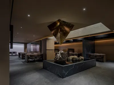 燈光柔和的餐廳內部，以石雕為中心藝術品，周圍環繞桌椅，營造溫暖而樸實的氛圍