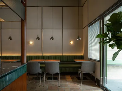 A well-lit dining area with a long table and multiple chairs, surrounded by modern decor and neutral tones