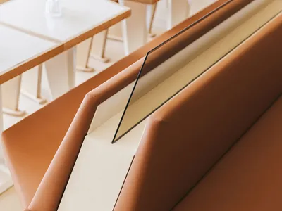 A modern seating area with a unique brown leather bench, part of a larger seating arrangement in a restaurant or waiting area, conveying comfort and relaxation