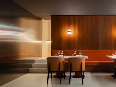 A cozy dining area with two long tables, wooden panel walls, and benches, set up for a meal or gathering
