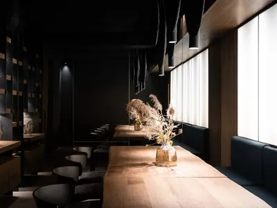 Warm and inviting restaurant interior with a wooden dining table, chairs, vases, and wood elements