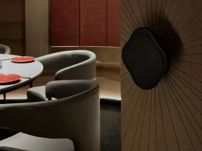 Cozy dining space with wooden walls and floors, dimly lit with chairs and tables for guests