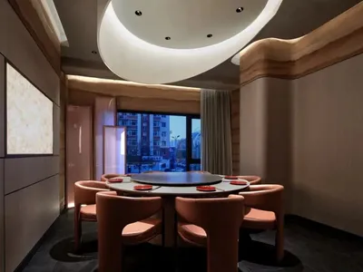 A well-lit dining area with a wooden table and leather chairs, visible outside views of a busy street