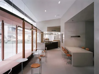 An open concept restaurant with a modern design, featuring a large dining area with tables and chairs, creating an inviting and comfortable atmosphere