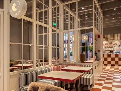 光線充足的餐廳，設有多張餐桌、椅子，以及大片窗戶讓自然光灑入空間
