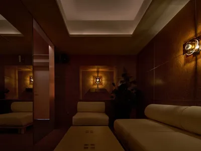 明亮客廳區擺放大型沙發與兩張椅子，對著鏡子營造舒適放鬆與社交氛圍