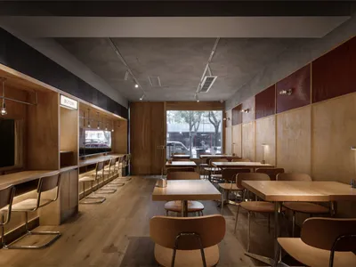 Modern restaurant interior with wooden floors, tables, and chairs, creating a warm and inviting atmosphere