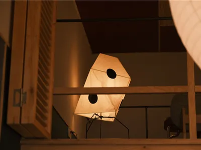 A dimly lit room with a chair in front of a window, natural light illuminating the space, and two lights on the left and right sides