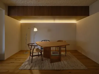 A well-lit living area with a wooden dining table and chairs, a couch, and a warm atmosphere