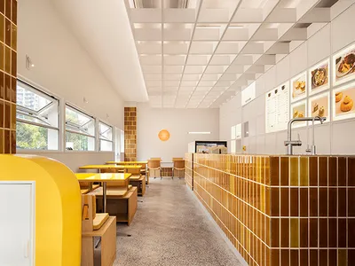 Bright and inviting dining space with multiple tables and chairs, natural light, and warm yellow walls