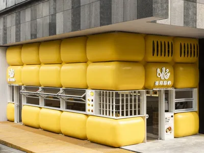 A warm and inviting Asian restaurant with yellow walls, yellow exterior, and large yellow balls on the outside wall, featuring dining tables and chairs inside