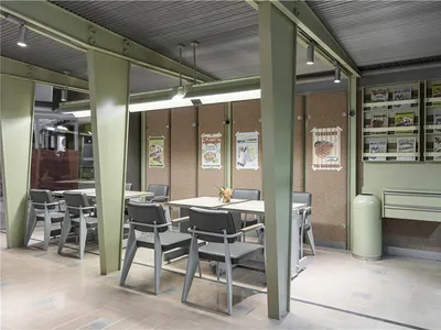 A cozy restaurant dining area with a greenish hue, soft lighting, and comfortable seating around a central table