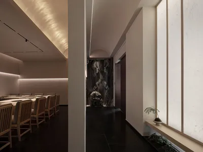 A dimly lit restaurant dining area with chairs, a dining table, and marble accents on the walls