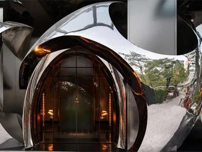 Elegant hotel lobby entrance with glass doors, metal frame, and chandeliers providing illumination