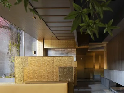 Luxurious hotel lobby with gold walls and ceiling, two benches, and a potted plant, creating a welcoming atmosphere